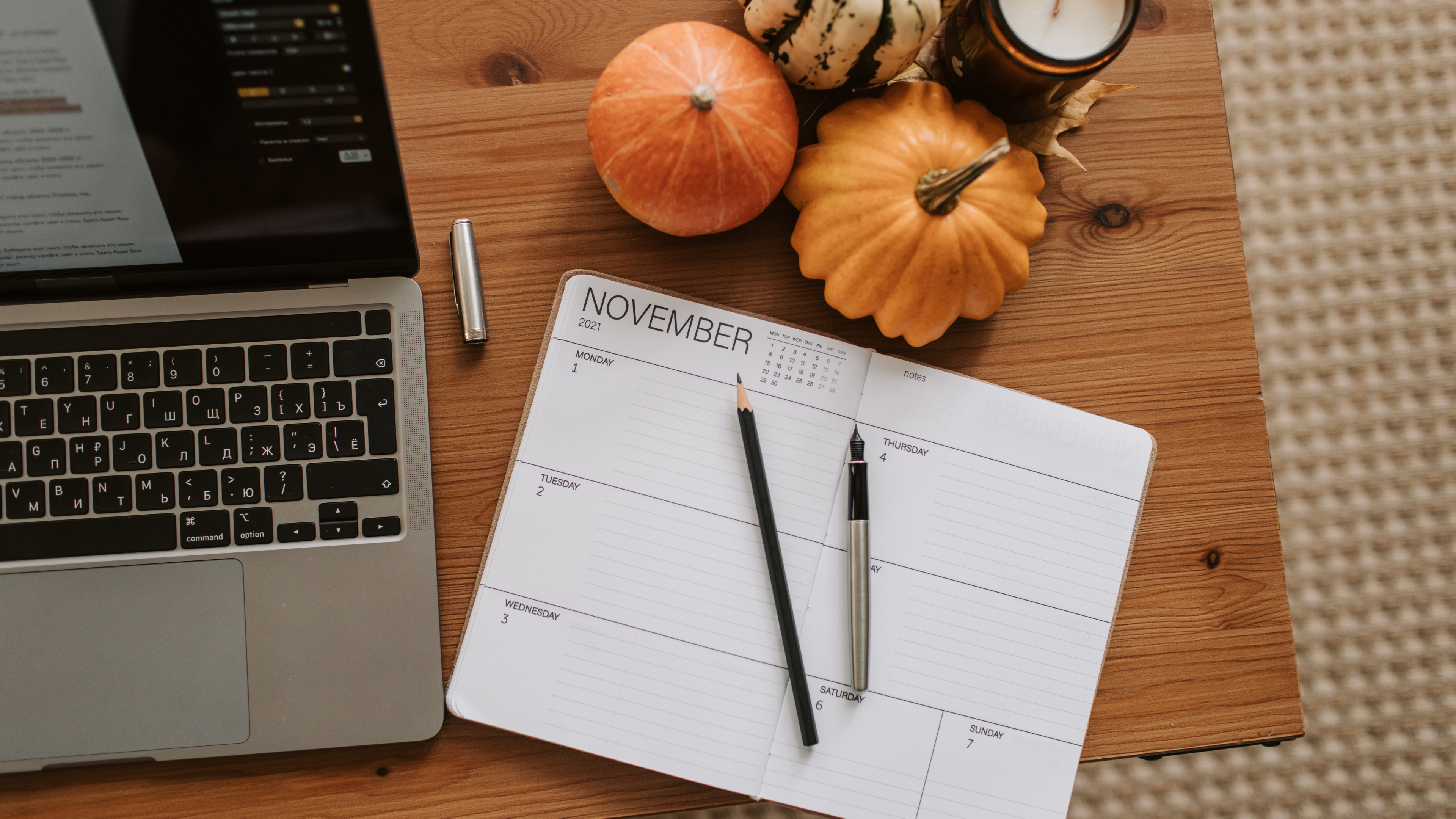 laptop, notebook, and pumpkins on a desk